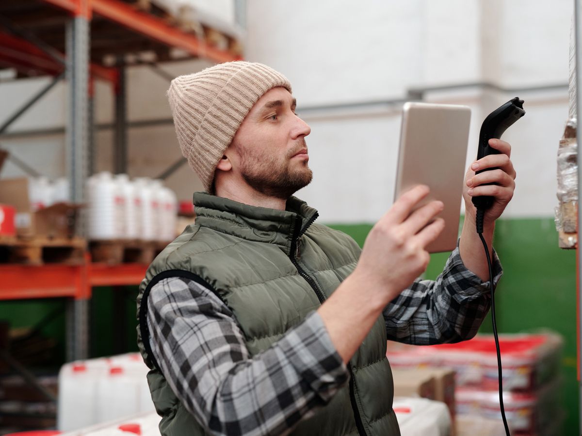 Warehouse worker using a handheld barcode scanner and tablet for stock-take